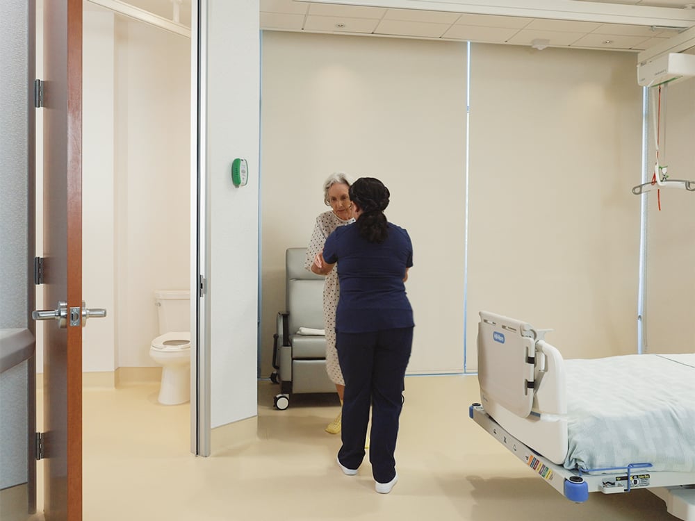 nurse assisting patient in hospital room