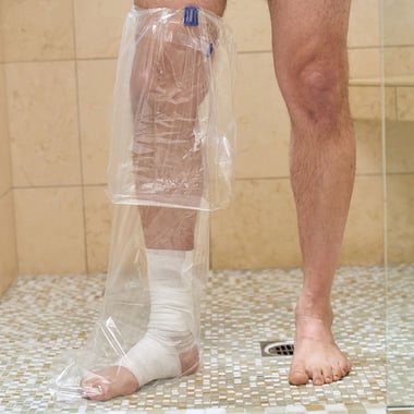 Patient wearing an AquaGuard Boot Shower Sleeve with Reusable locking water seal band.