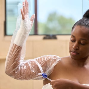 AquaGuard Arm Shower Sleeve and reusable locking water seal band in use on woman's arm. Close up image.