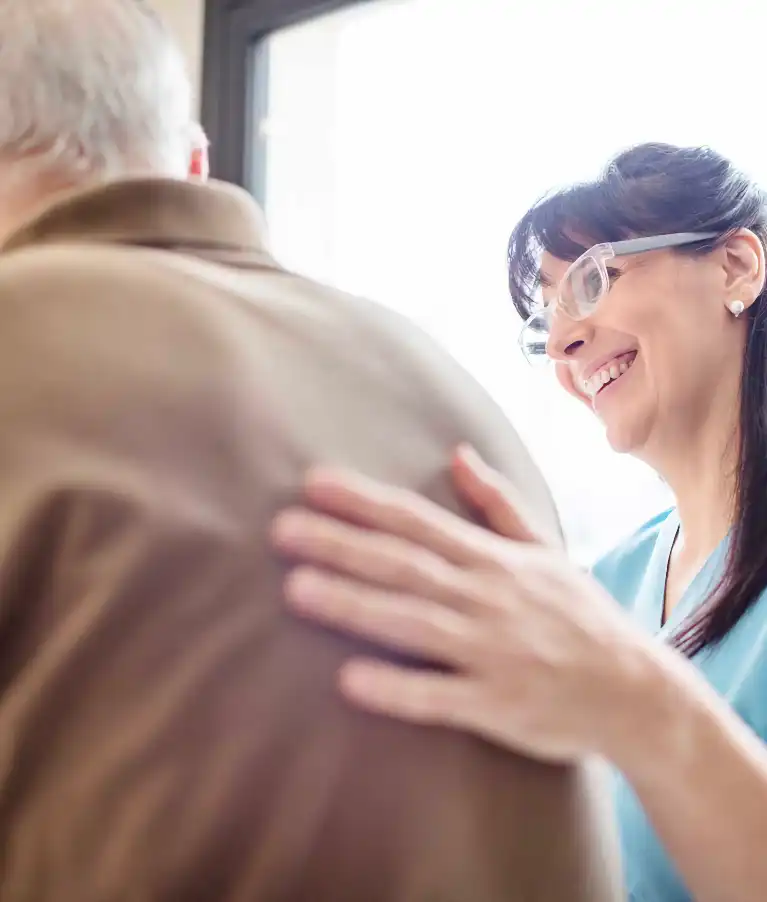 nurse-smiling-with-hand-on-patients-back-767